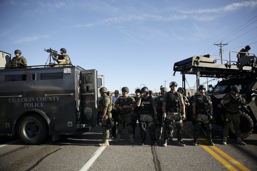 Police in riot gear watch protesters in Ferguson, Mo. on Wednesday, Aug. 13, 2014. On Saturday, Aug. 9, 2014, a white police officer fatally shot Michael Brown, an unarmed black teenager, in the St. Louis suburb. (AP Photo/Jeff Roberson)